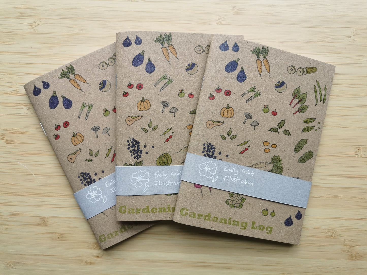 Three gardening logs with vegetable illustrations on a wooden surface