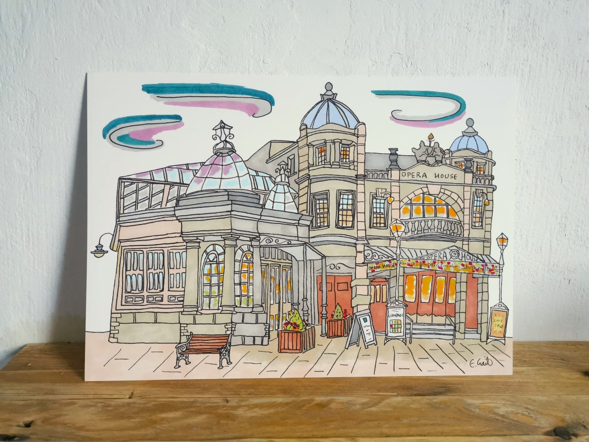 Real Life image of colorful illustration of Buxton Opera House, placed on a wooden surface with a white background