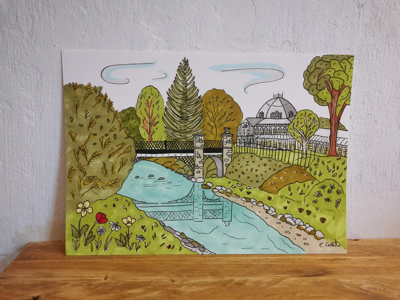 Colorful illustration of a Buxton Pavilion Gardens with trees, a bridge, and the pavilion on a white background.