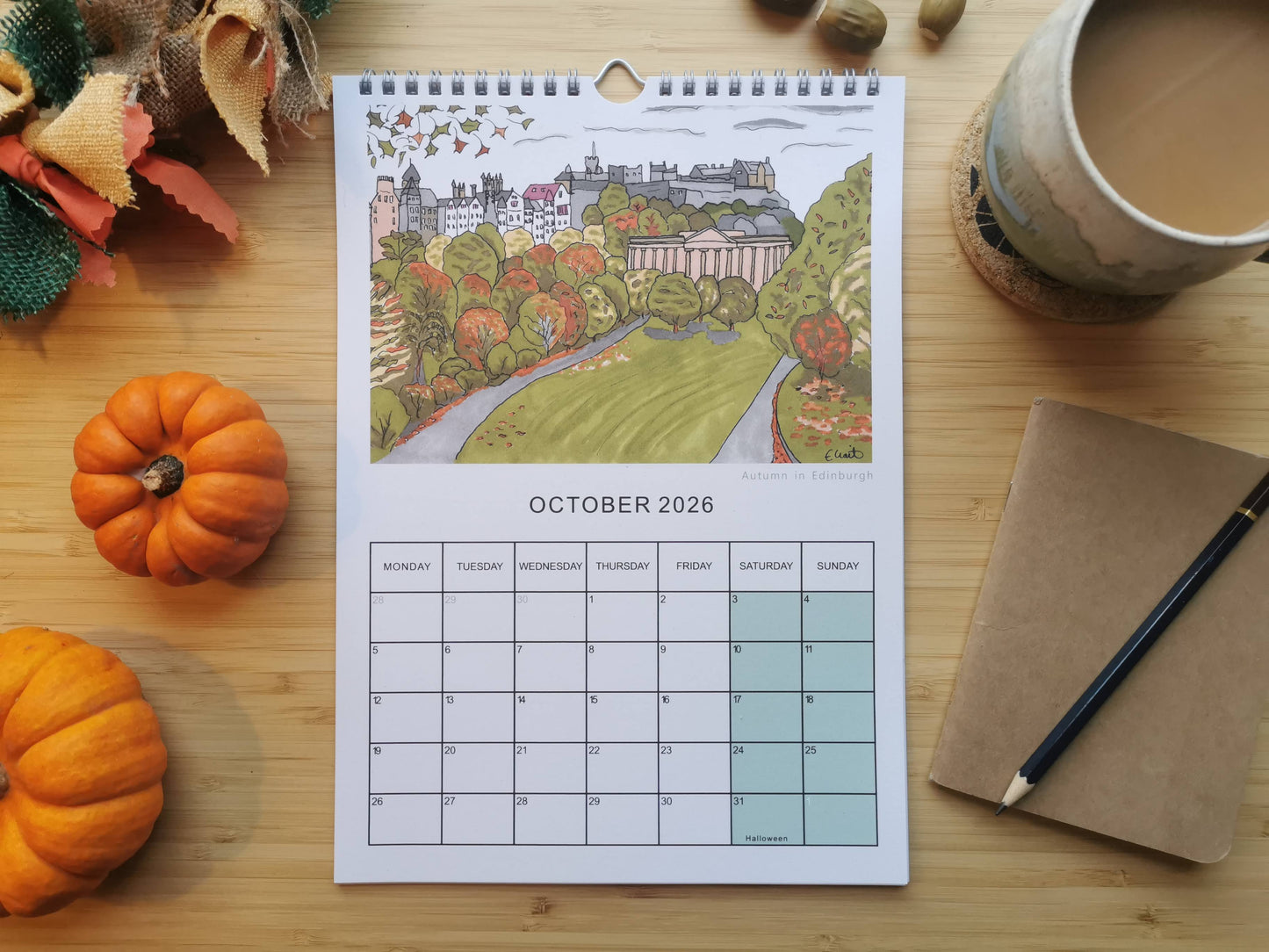 October 2026 calendar on a wooden table with pumpkins and a cup of coffee.