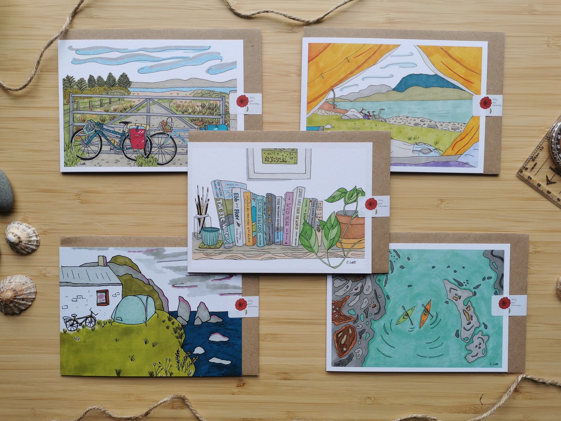 Five illustrated cards on a wooden surface with various scenes of adventures including kayaks, cycling, camping and hiking.