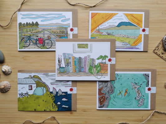 Five illustrated cards on a wooden surface with various scenes of adventures including kayaks, cycling, camping and hiking.
