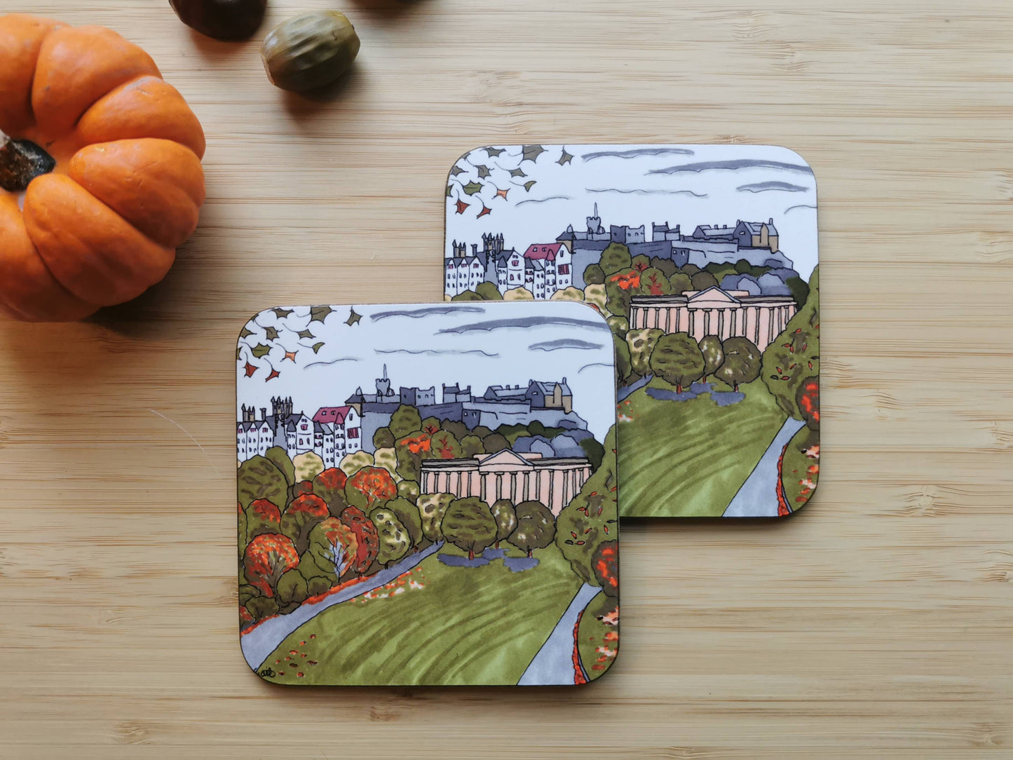 Two coasters of Edinburgh in Autumn on a wooden surface with a pumpkin.