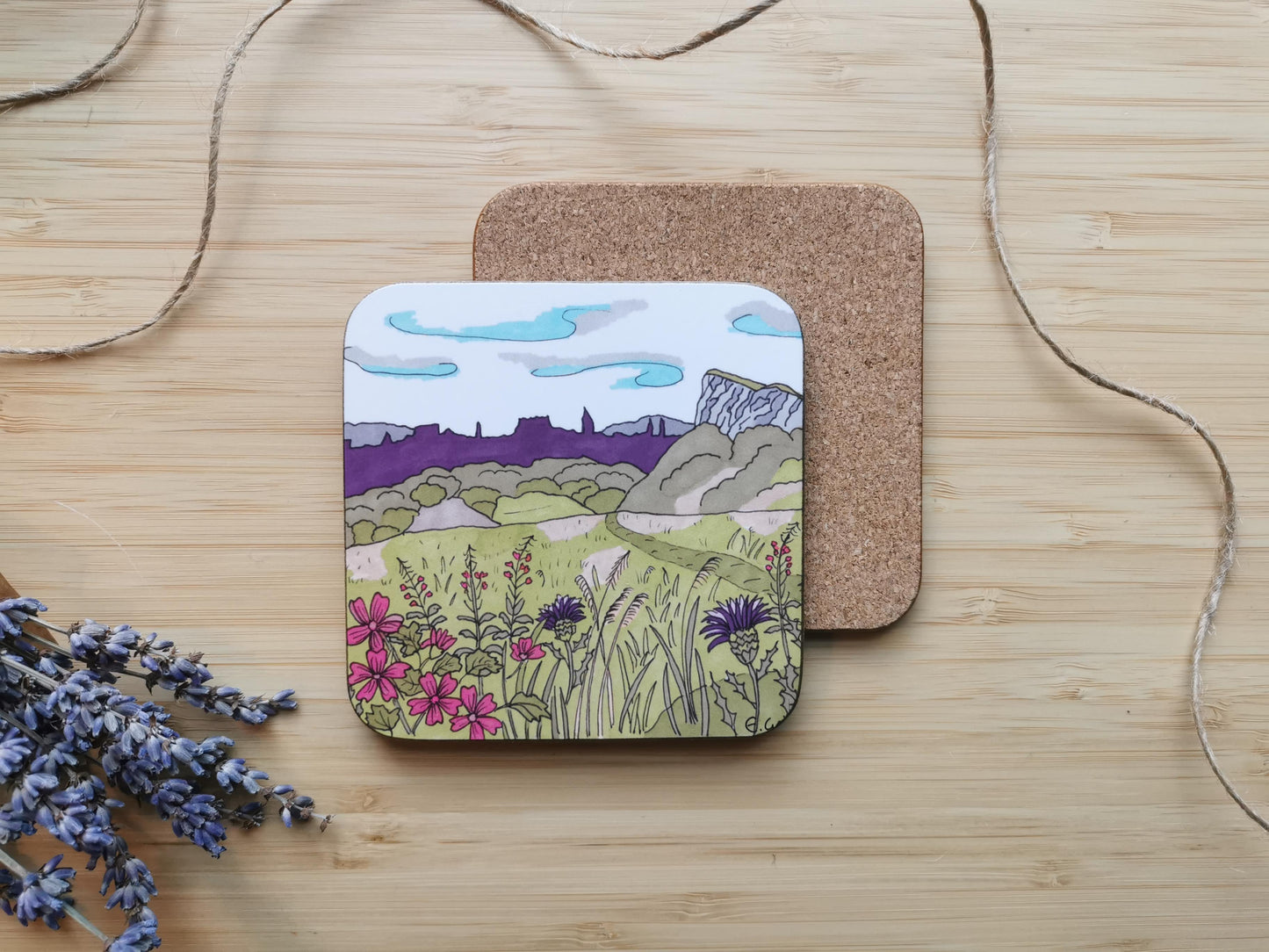 Coaster with an illustration of Salisbury Crags, Arthur's Seat in Edinburgh with the skyline of the city and rosebay willowherbs in the foreground.
