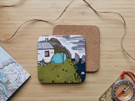 Coaster with an illustration of a tent, bike and bothy on the coast with the sky turning pink at dusk.