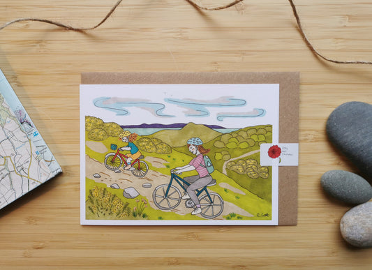 Greeting card with illustration of two people, a mum and a daughter cycling up hill with Edinburgh, the sea and Arthur's seat in the background.