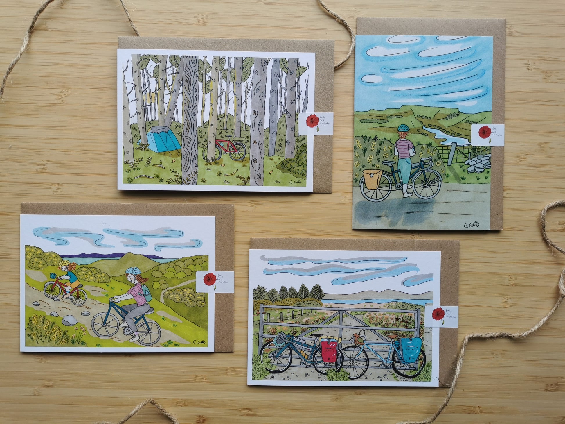 Four illustrated greeting cards on a wooden surface with cyclists and nature scenes.
