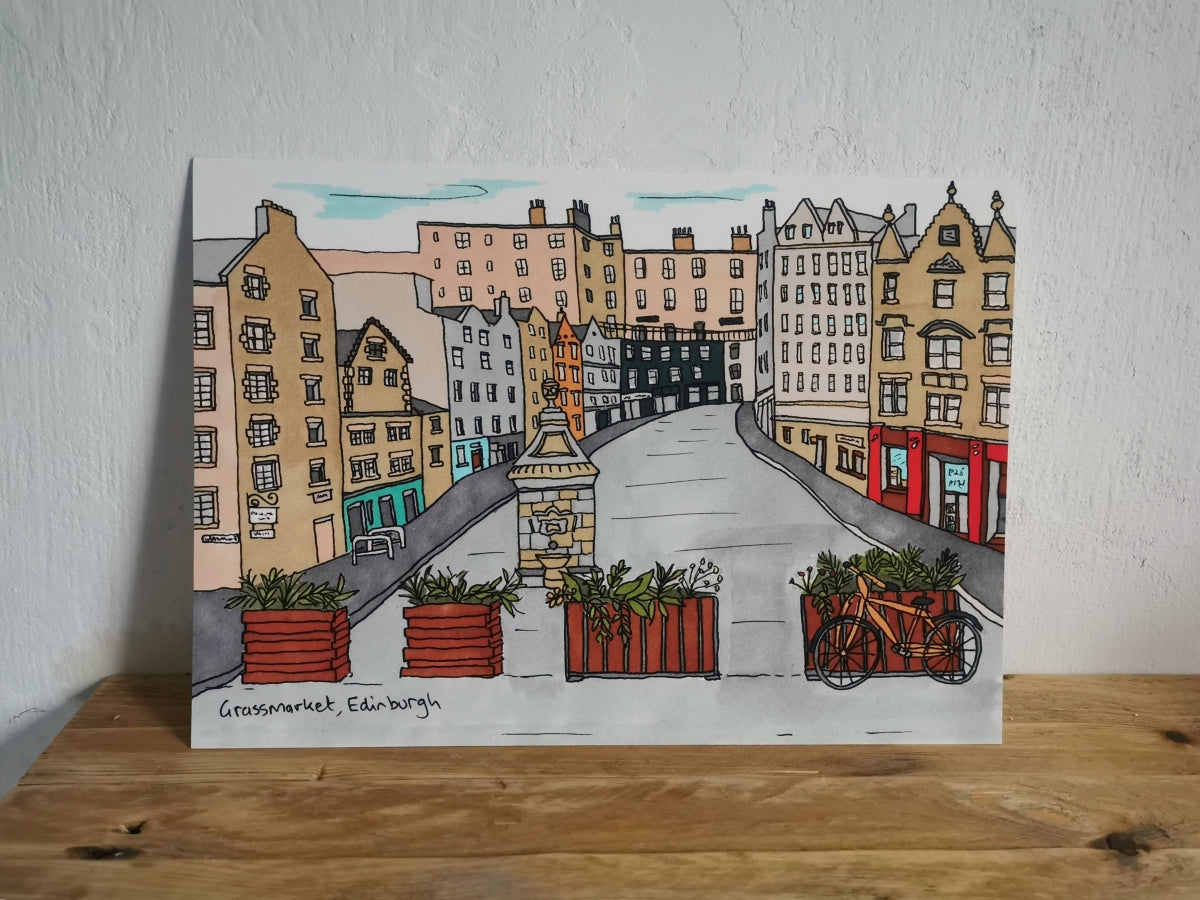 Illustration of Victoria Street in Edinburgh with buildings and a bicycle on a wooden surface.
